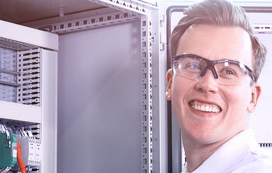 Smiling Adwatec worker in front of an electrical cabinet