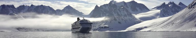 A cruiser sailing in winter in front of mountains