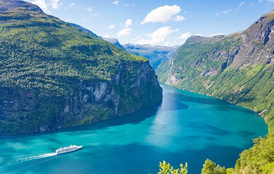 A ship sailing in the fjord landscape