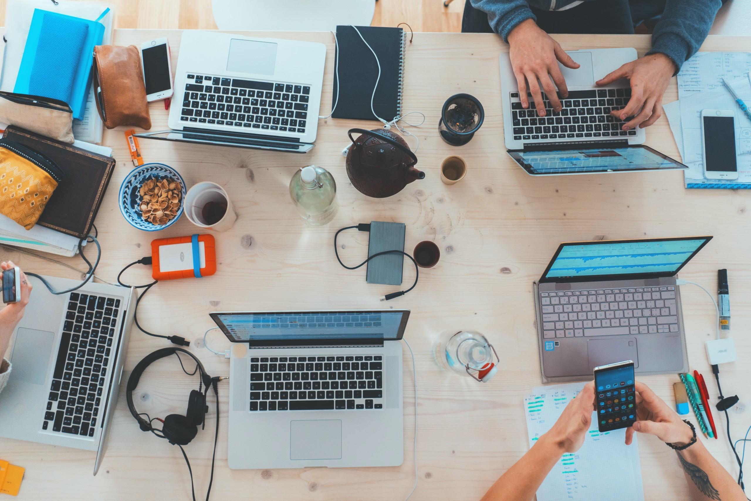People working with laptops and mobile phones by the table